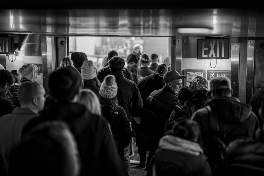 A bustling crowd exits a ferry in New York, captured in black and white.